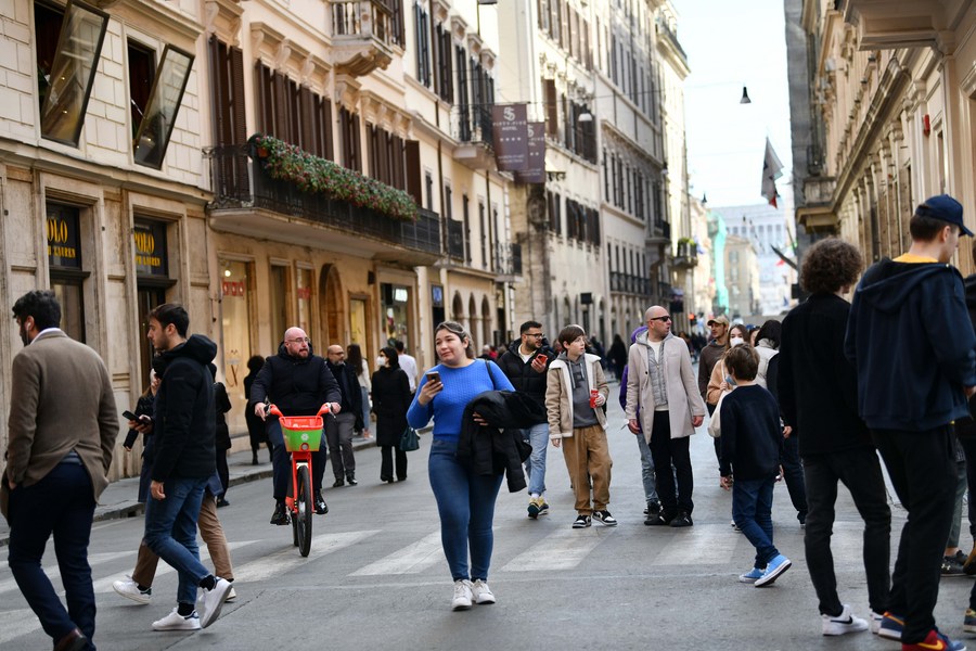 A pedestrians, wearing a protective face mask, walks past Louis Vuitton  store in downtown Rome, Italy