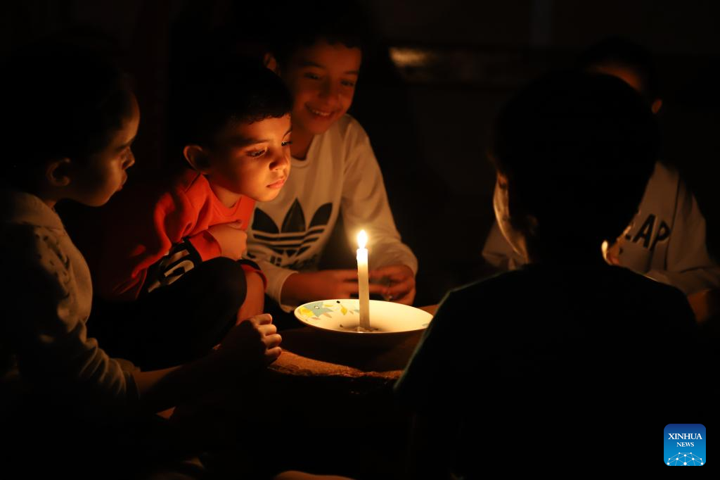 A Palestinian boy poses behind candles during a power outage