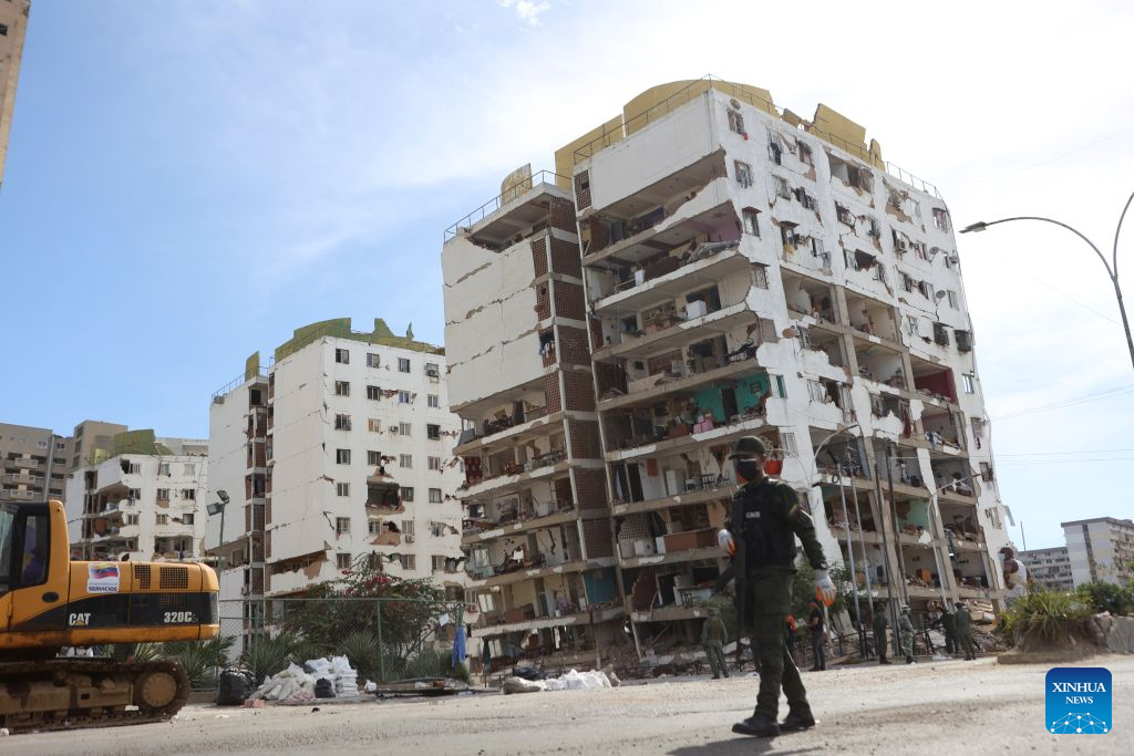 A member of the Bolivarian National Armed Forces walks past damaged buildings in Playa Grande, La Guaira state, Venezuela, June 28, 2026