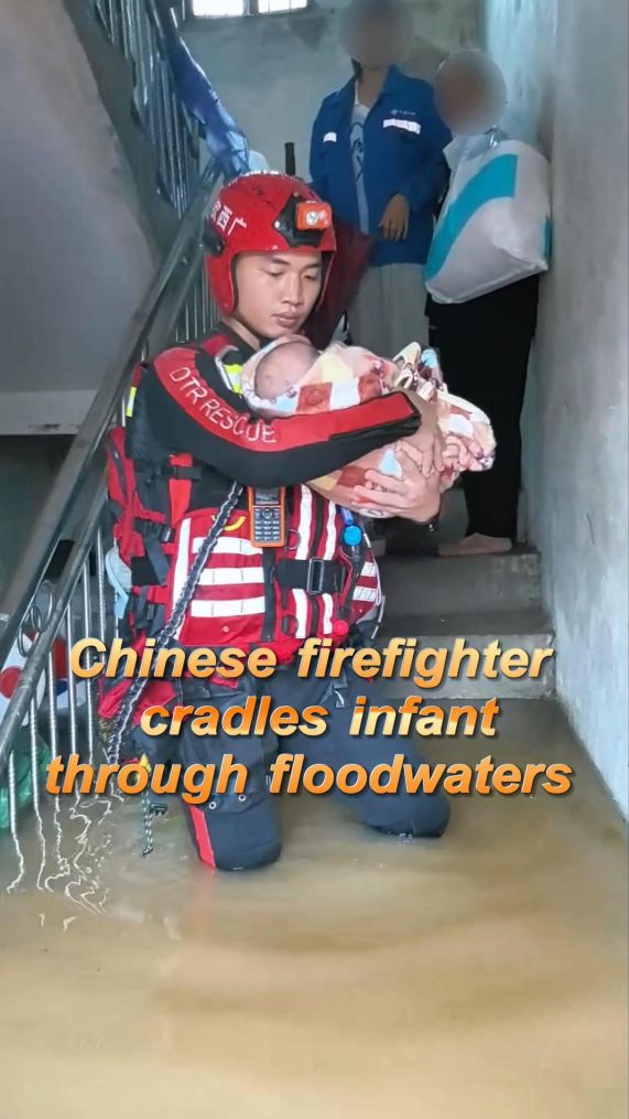 Firefighter carries infant to safety through floodwaters in south China