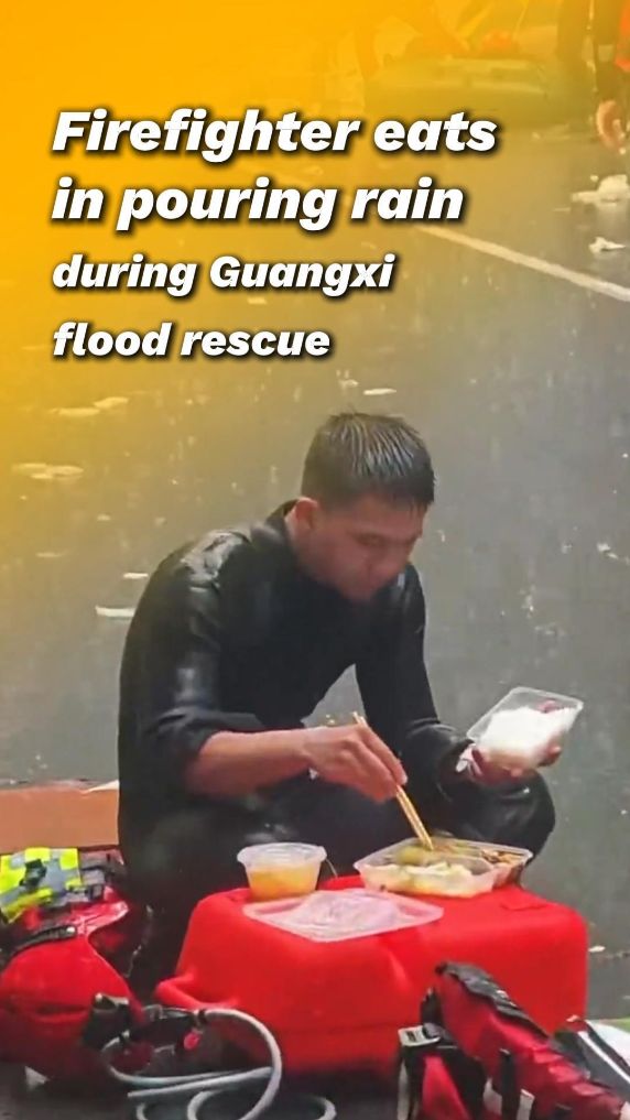 Firefighter eats in pouring rain during Guangxi flood rescue